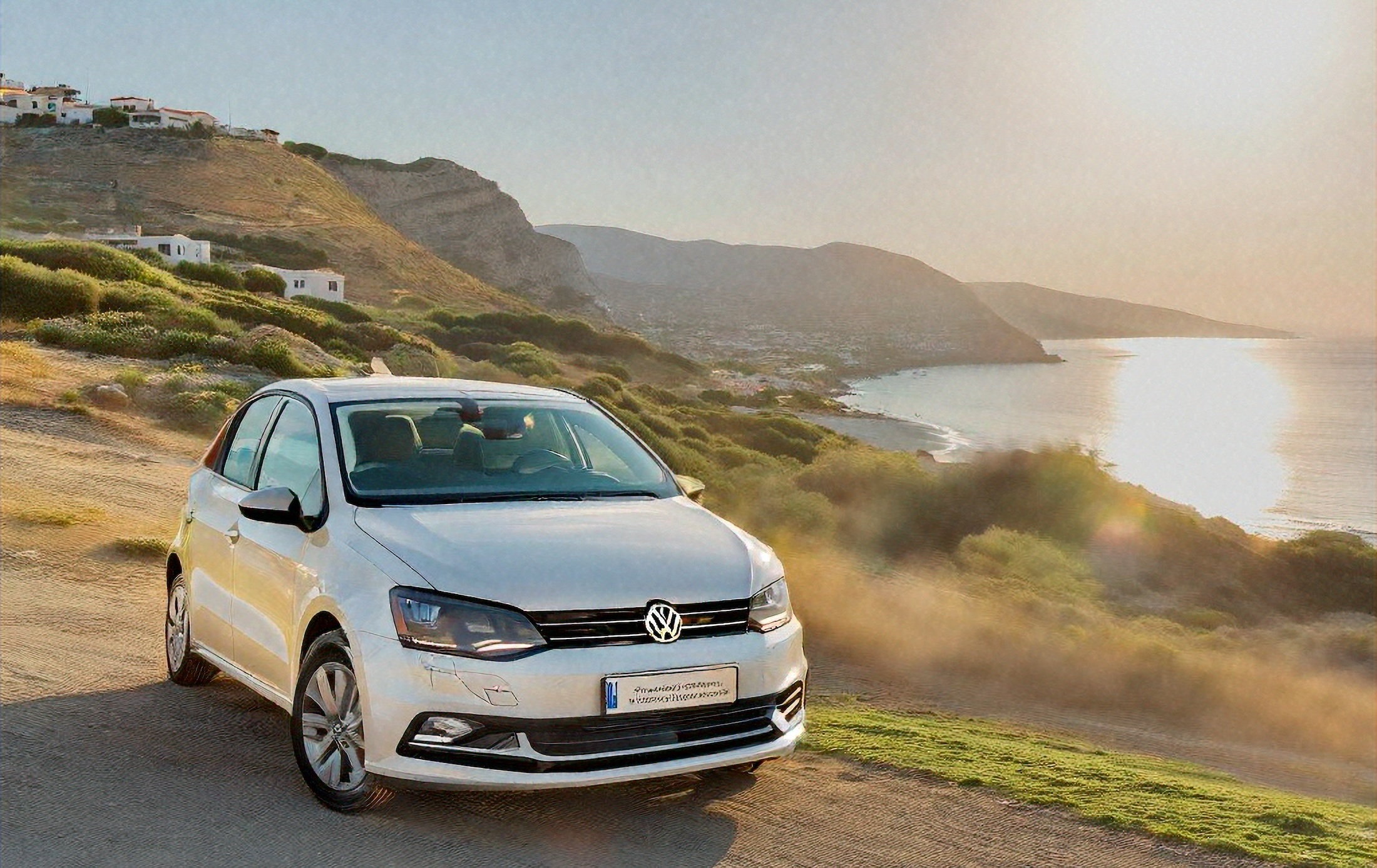Renting a car in Crete can prove cost efficient and convenient volkswagen polo in beach in a summer evening